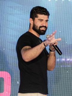 Cícero Alves no palco, gesticulando com o microfone na mão
